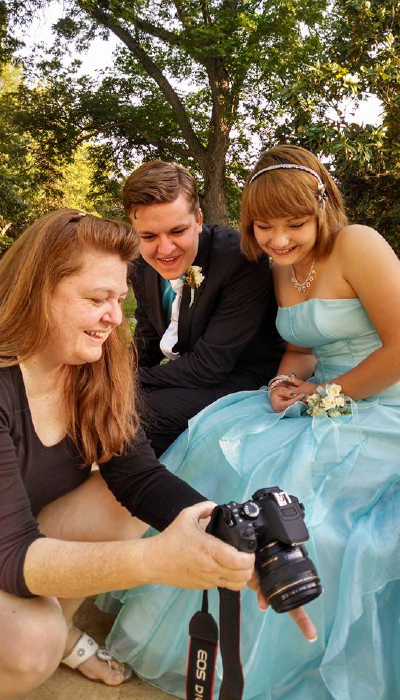dusty holding a camera and showing two subjects their photos